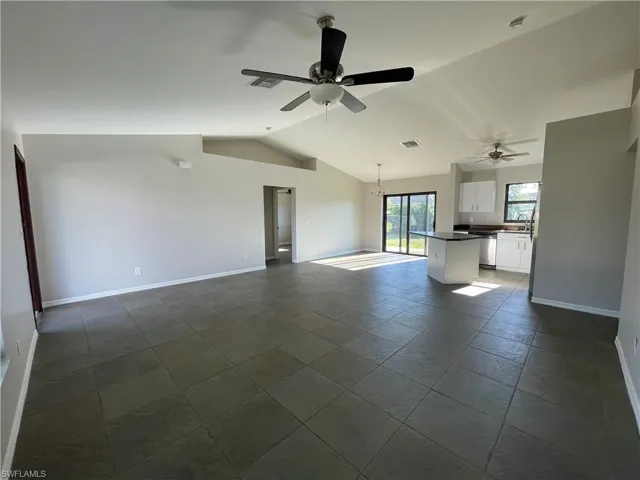 Unfurnished living room featuring lofted ceiling, ceiling fan, and a chandelier