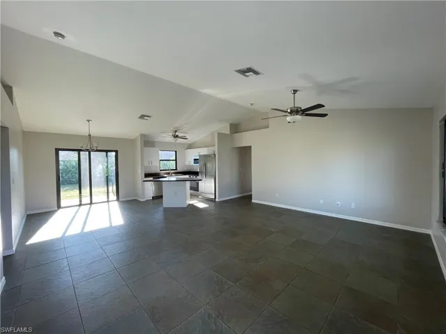 Unfurnished living room featuring a chandelier, vaulted ceiling, and a ceiling fan