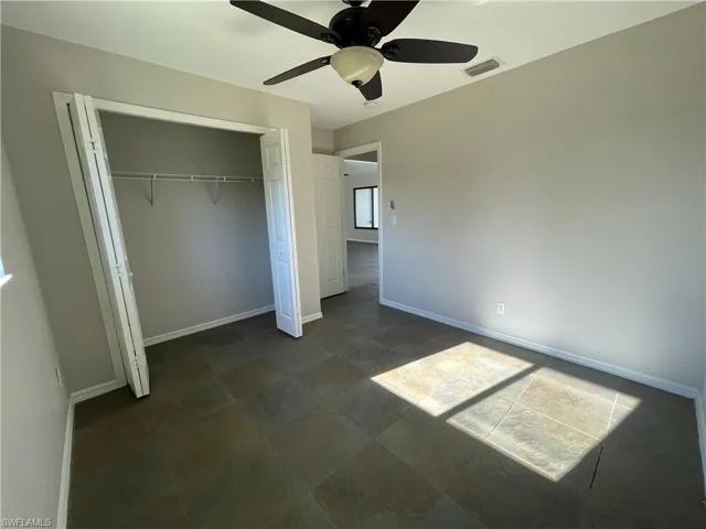 Unfurnished bedroom with ceiling fan and a closet