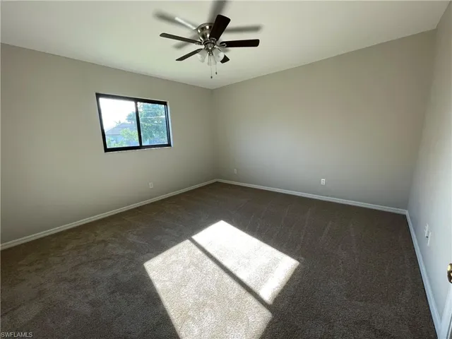 Carpeted empty room with baseboards and ceiling fan