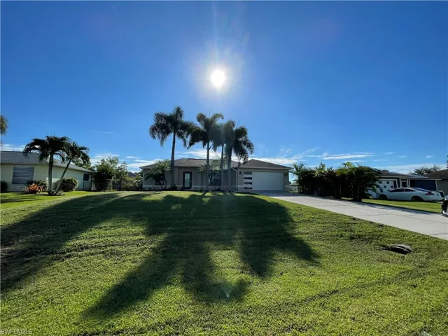 Single story home featuring driveway, a front yard, and an attached garage