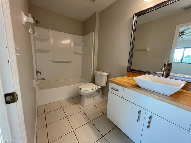 Bathroom with tub / shower combination, vanity, light tile patterned floors, and a ceiling fan