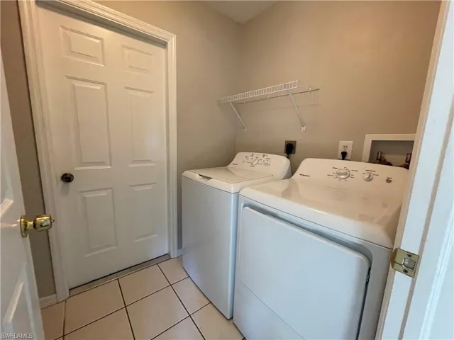 Washroom with light tile patterned flooring and independent washer and dryer
