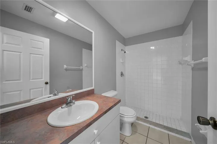 Bathroom featuring a stall shower, vanity, and light tile patterned floors