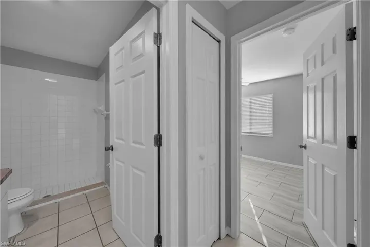 Bathroom with tiled shower, a closet, and vanity