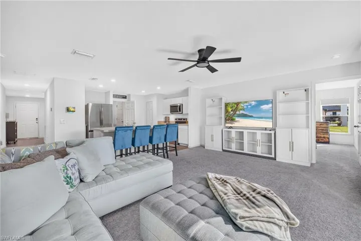 Open-concept floor plan featuring wall-to-wall carpeting, recessed lighting, a modern ceiling fan, and built-in white cabinetry