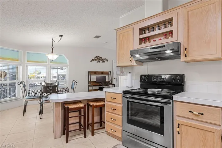 Kitchen has stainless appliances and snack bar.