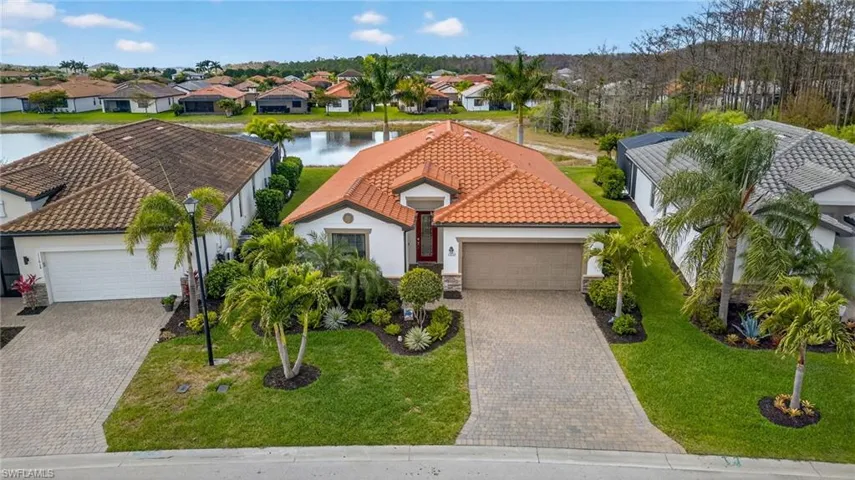 Mediterranean / spanish-style home with a garage, a tile roof, a front yard, a water view, and stucco siding