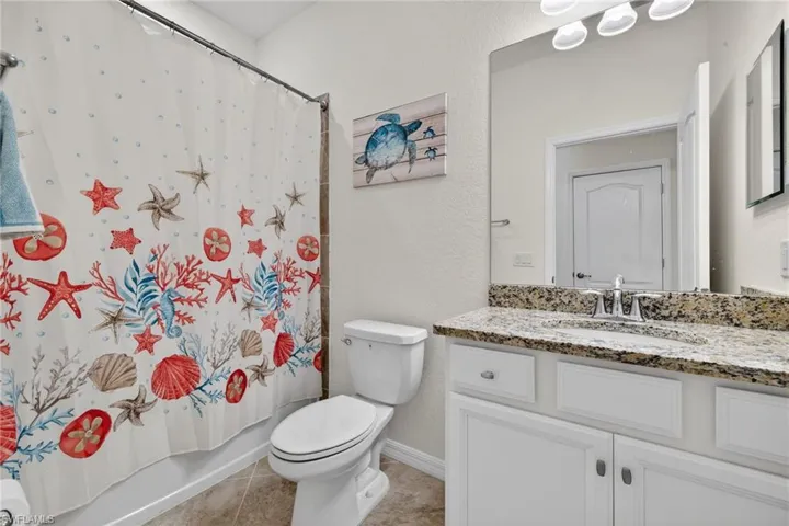 Bathroom featuring vanity, a textured wall, shower / bath combo, and light tile patterned flooring