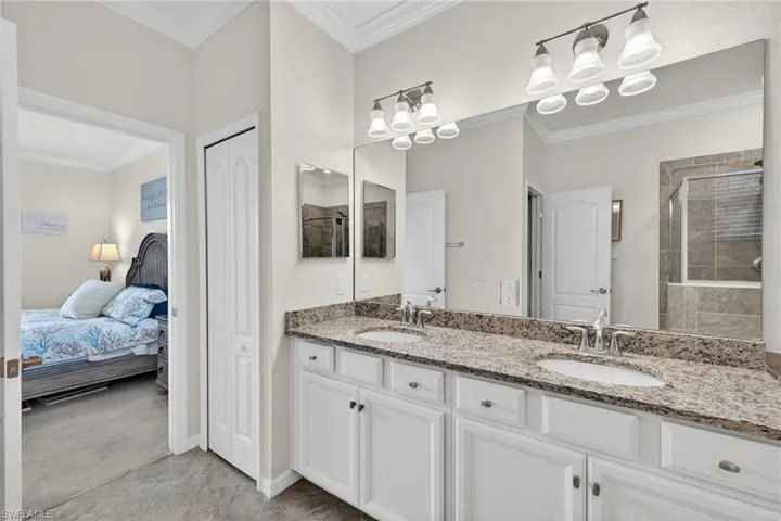 Bathroom with a closet, double vanity, crown molding, a stall shower, and ensuite bath