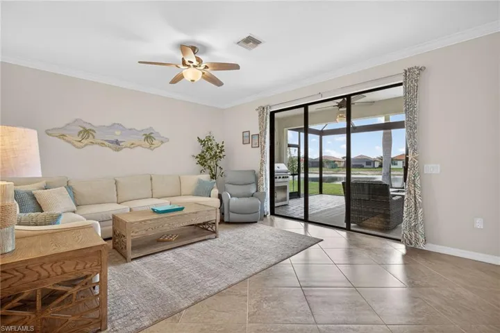 Living room with a ceiling fan, crown molding, and light tile patterned floors