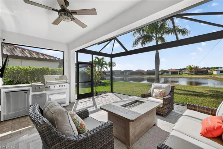 Sunroom with an outdoor kitchen and area to lounge, a ceiling fan, a water view, a residential view, and an outdoor fire pit