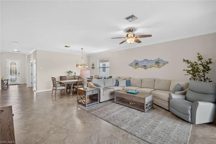 Living area featuring ornamental molding, ceiling fan, and light tile patterned flooring