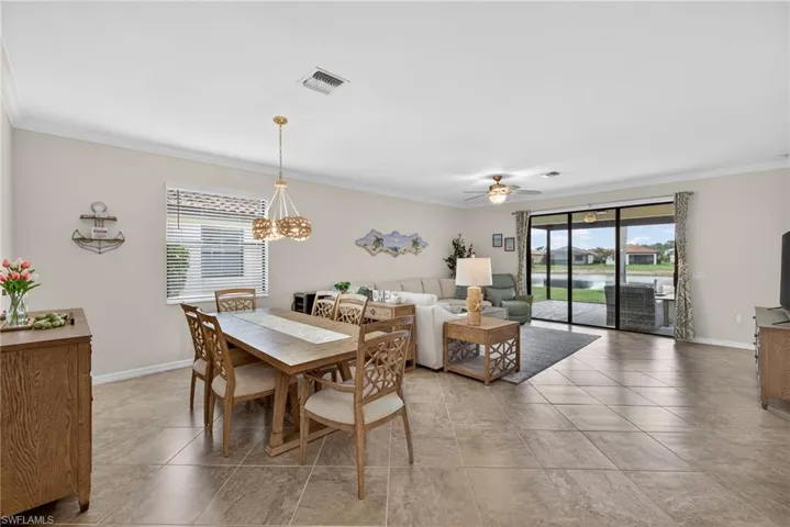 Dining area with crown molding, ceiling fan, light tile patterned flooring, and suspended lighting