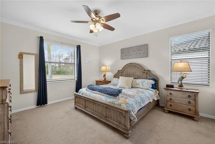 Bedroom with crown molding, light carpet, and a ceiling fan