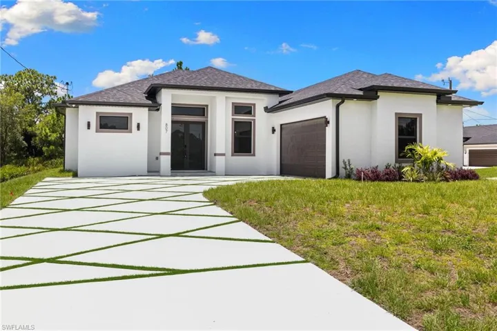 Prairie-style house with an attached garage, stucco siding, french doors, a front lawn, and roof with shingles