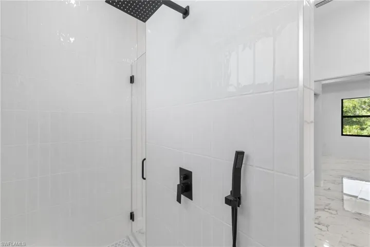 Full bathroom featuring a shower stall and marble tiled floors