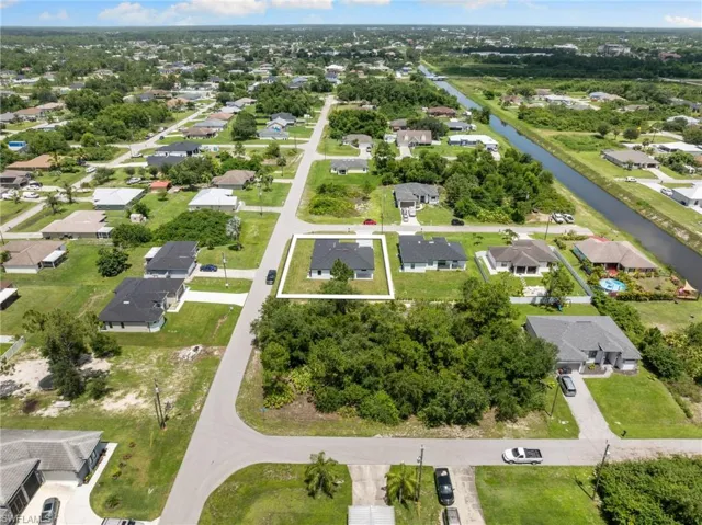 Aerial view of property and surrounding area featuring a nearby body of water and nearby suburban area