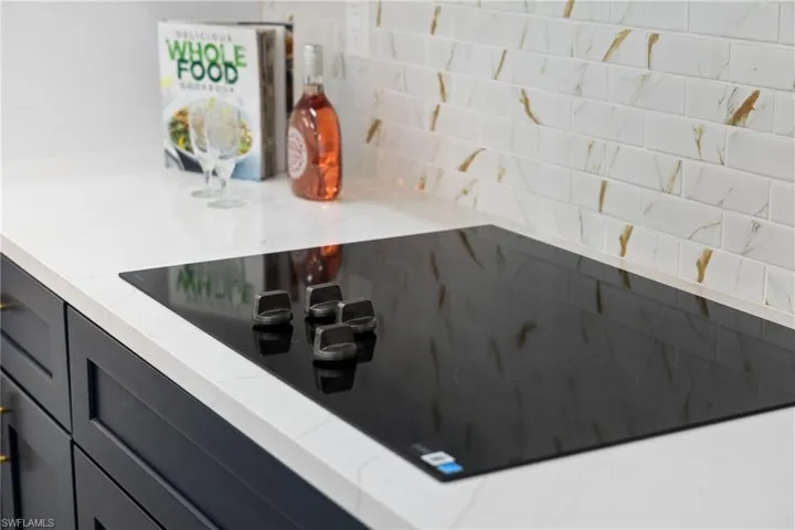 Kitchen view of black electric stovetop and backsplash