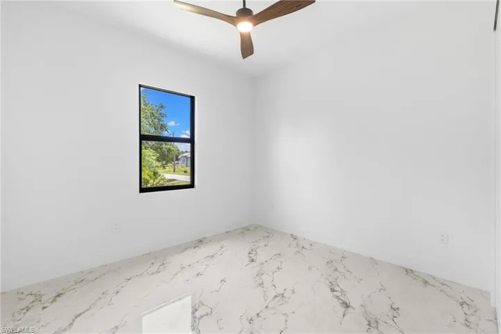 Bedroom with ceiling fan and marble finish flooring
