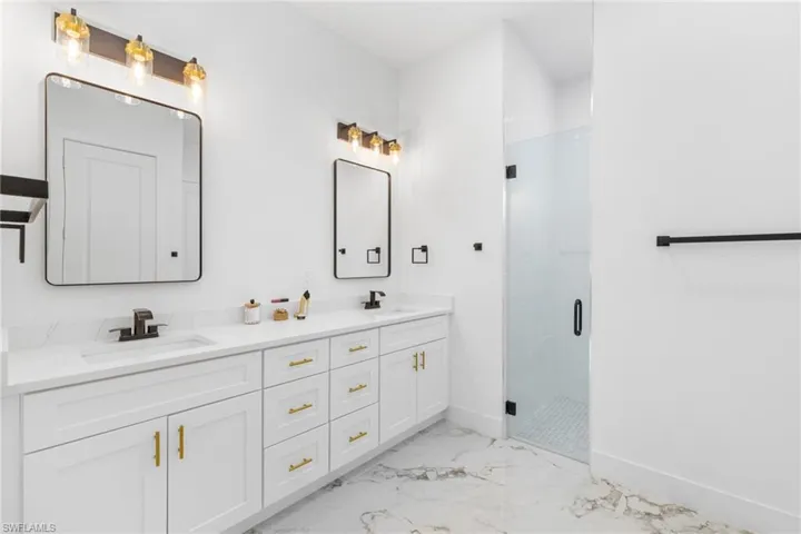 Master Bathroom with marble look tiles, double vanity, and a shower stall