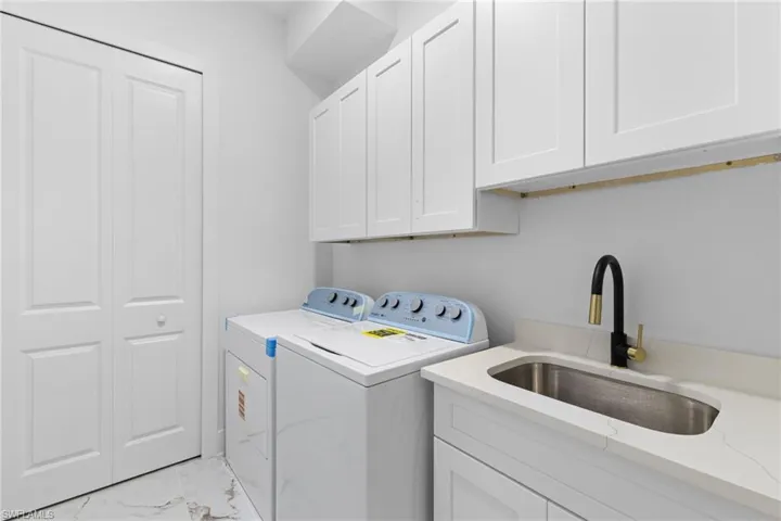 Idependent isnide Laundry with washer and dryer, cabinet space, and light marble finish flooring