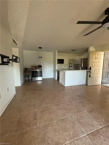 Unfurnished living room featuring ceiling fan and a textured ceiling