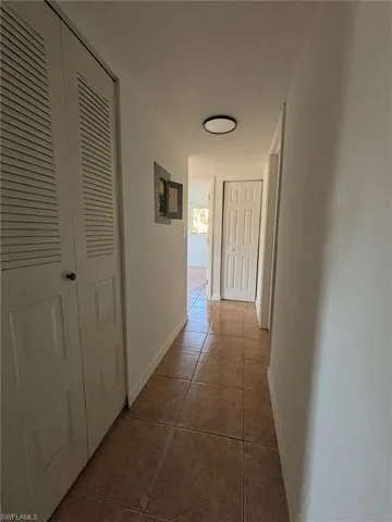 Corridor with dark tile patterned flooring and baseboards