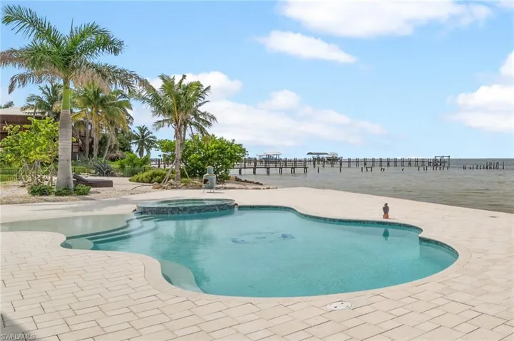 View of swimming pool featuring a pool with connected infinity edge spa , a patio area, and a water view