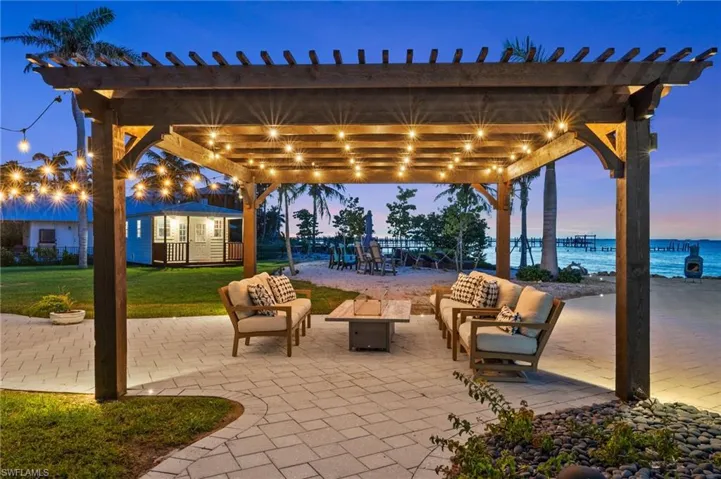View of patio with an outdoor living space with a fire pit, a pergola, and a water view also pictured in rear is the storage shed.