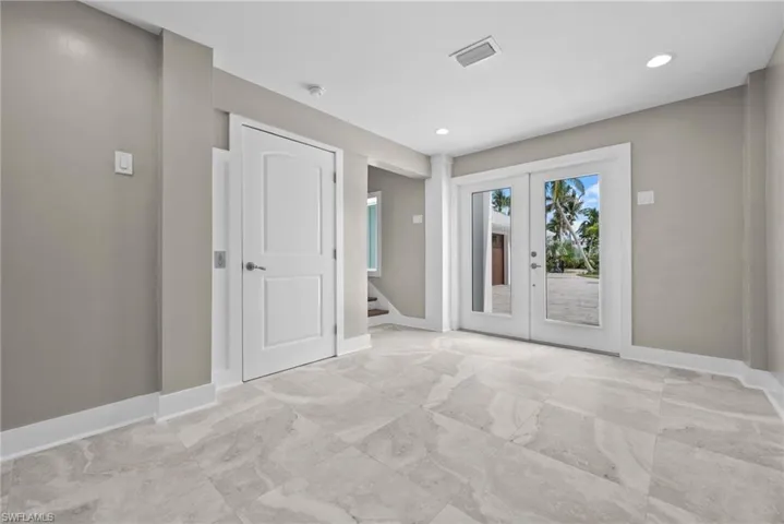 Front entry way room with french doors, stairs, light marble finish tile flooring, recessed lighting and elevator.