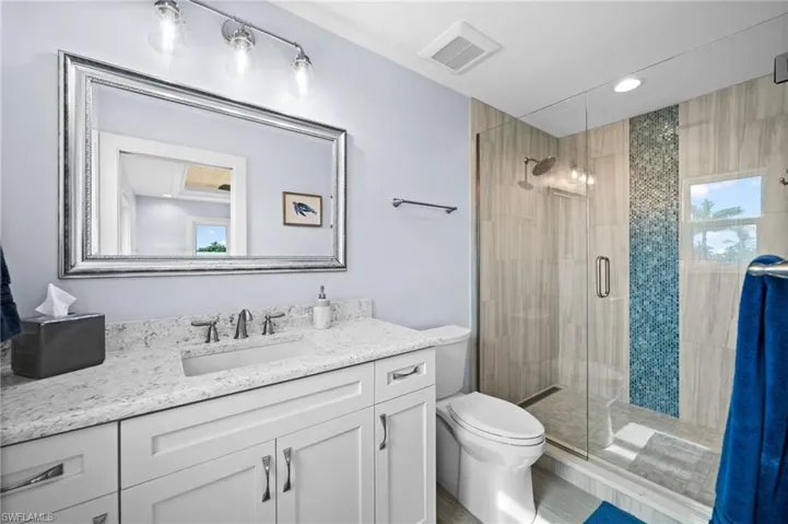 Bathroom with vanity, a shower stall, natural light, and recessed lighting