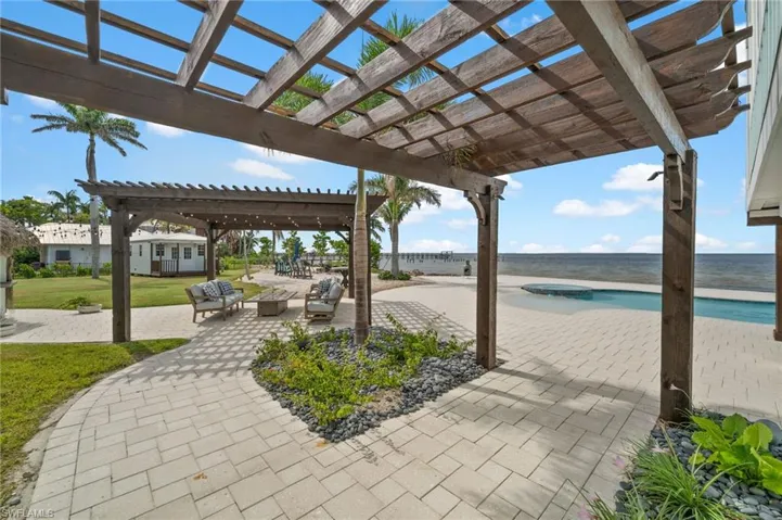 View of patio / terrace with outdoor lounge area, a pergola, a water view, and a pool with connected infinity edge hot tub