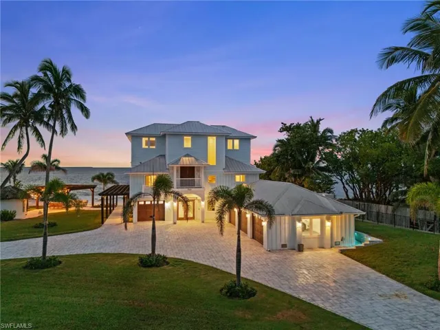 Beach house with a metal roof, decorative driveway, two pergolas, tiki bar,  a water view, and 4 garages.