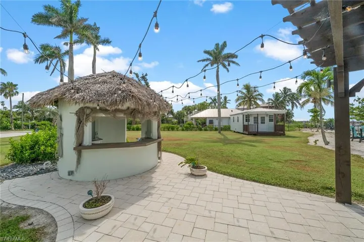 View of tiki bar with thatch roof and string lights for entertaining.