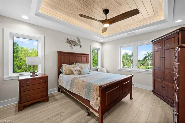 Bedroom featuring a recessed wood ceiling, woodgrain ceiling fan, and recessed lighting with plenty of natural light.
