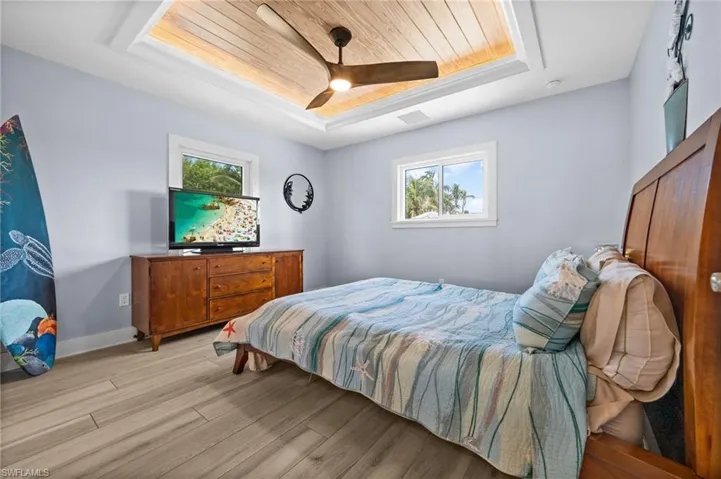 Bedroom featuring a raised ceiling, light wood-style floors, wood ceiling, and ceiling fan
