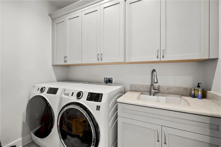 second floor laundry room featuring cabinet space and washer, clothes and sink.