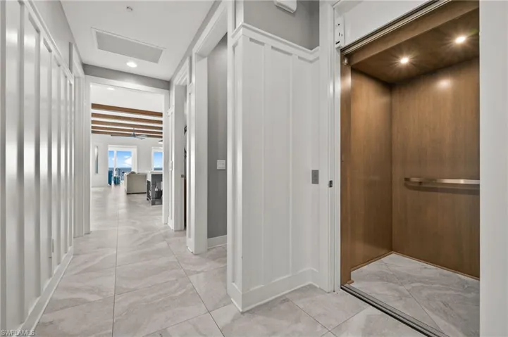 Corridor with light marble finish flooring and elevator on the second floor.