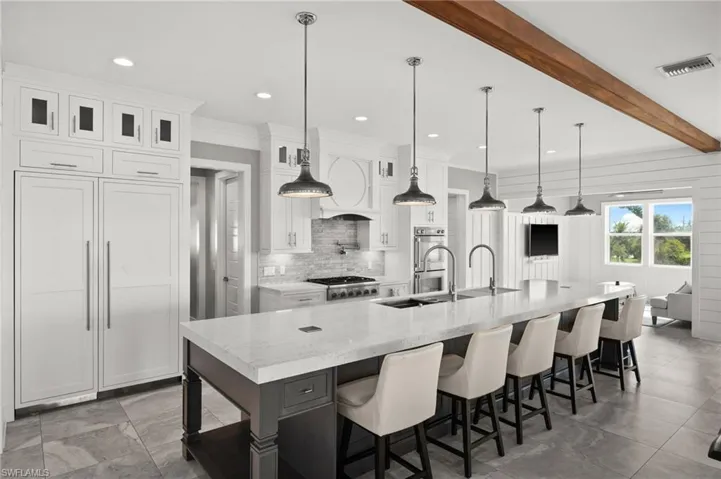 Kitchen featuring decorative backsplash, white cabinets, a spacious island, glass insert cabinets, and recessed lighting. Custom cabinet front Thermador refrigerator,  gas stove, double ovens and pot filler.