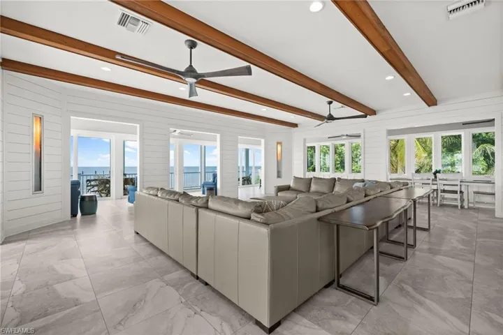 Living room featuring two ceiling fans, beamed ceiling, natural light, recessed lighting, two Hellfire 360 Contemporary gas fireplaces and a water view
