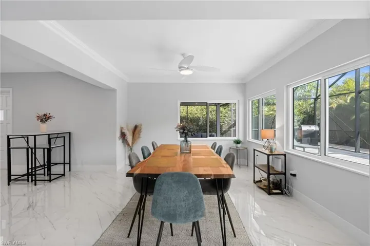 Dining space featuring crown molding, baseboards, a ceiling fan, and marble finish floor