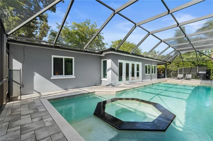View of swimming pool with french doors, a pool with connected hot tub, a patio, and a lanai