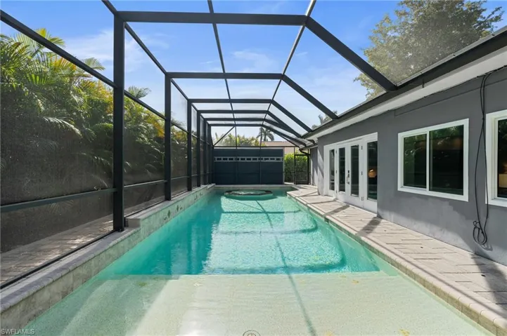 Outdoor pool featuring a patio area, french doors, and glass enclosure