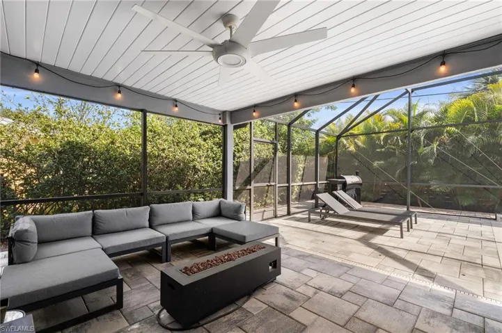 View of patio featuring an outdoor living space with a fire pit, glass enclosure, and a ceiling fan