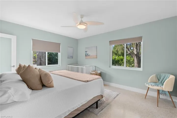 Bedroom with carpet flooring, ceiling fan, baseboards, and multiple windows