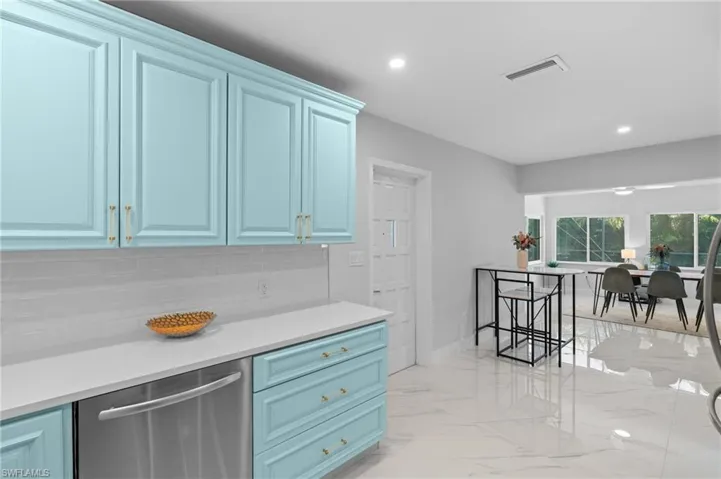 Kitchen with blue cabinets, visible vents, marble finish floor, and dishwasher