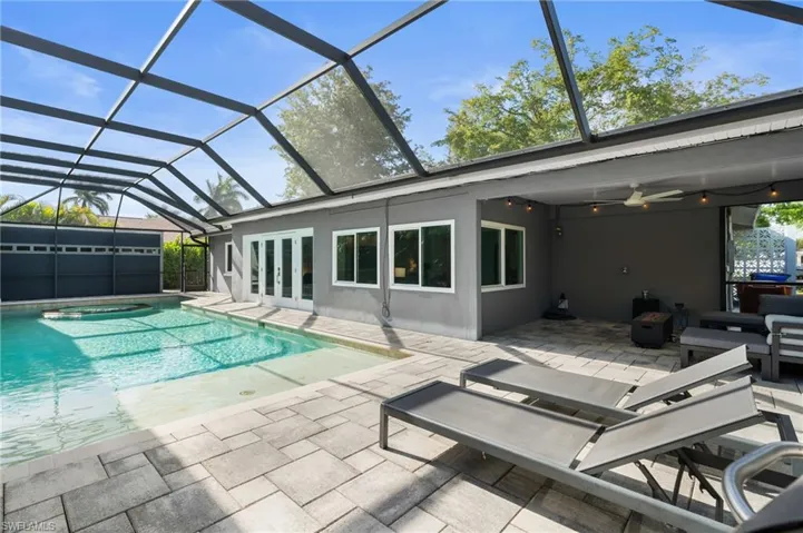 View of swimming pool featuring a patio, french doors, glass enclosure, and ceiling fan