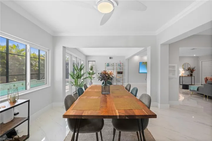 Dining area featuring a ceiling fan, marble finish floor, baseboards, and ornamental molding