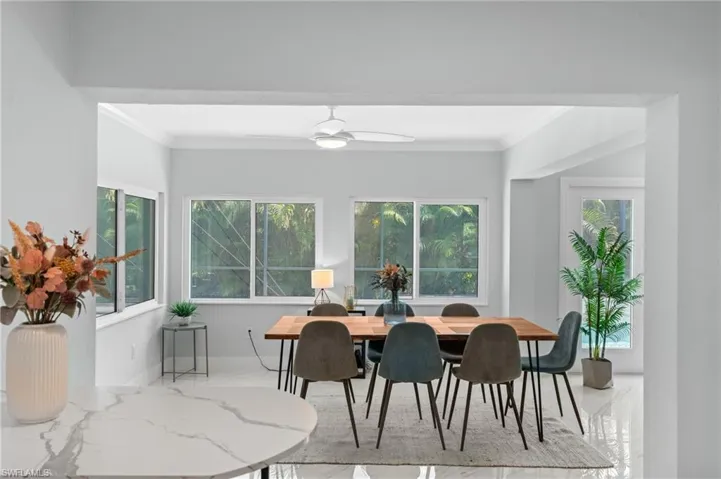 Dining room with ornamental molding, ceiling fan, marble finish floor, and baseboards